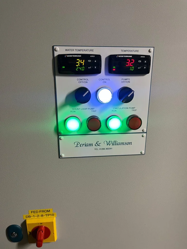 Close-up of a control panel with temperature displays, illuminated pump controls and a Periam & Williamson name plate