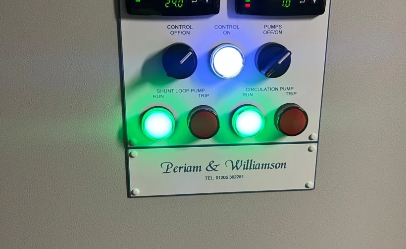 Close-up of a control panel with temperature displays, illuminated pump controls and a Periam & Williamson name plate