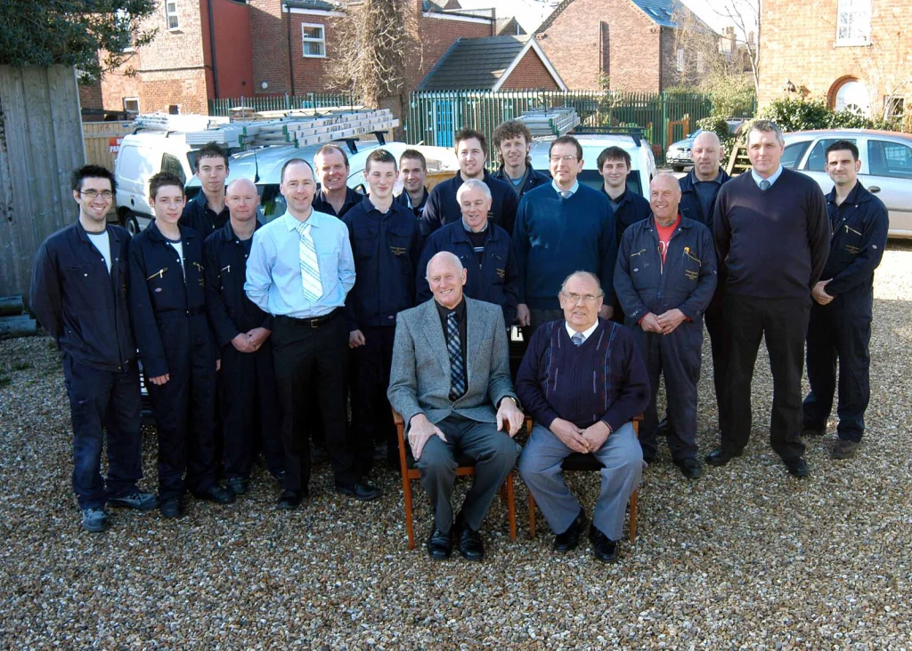 Group photograph of Periam & Williamson staff gathered outdoors, with two men seated at the front